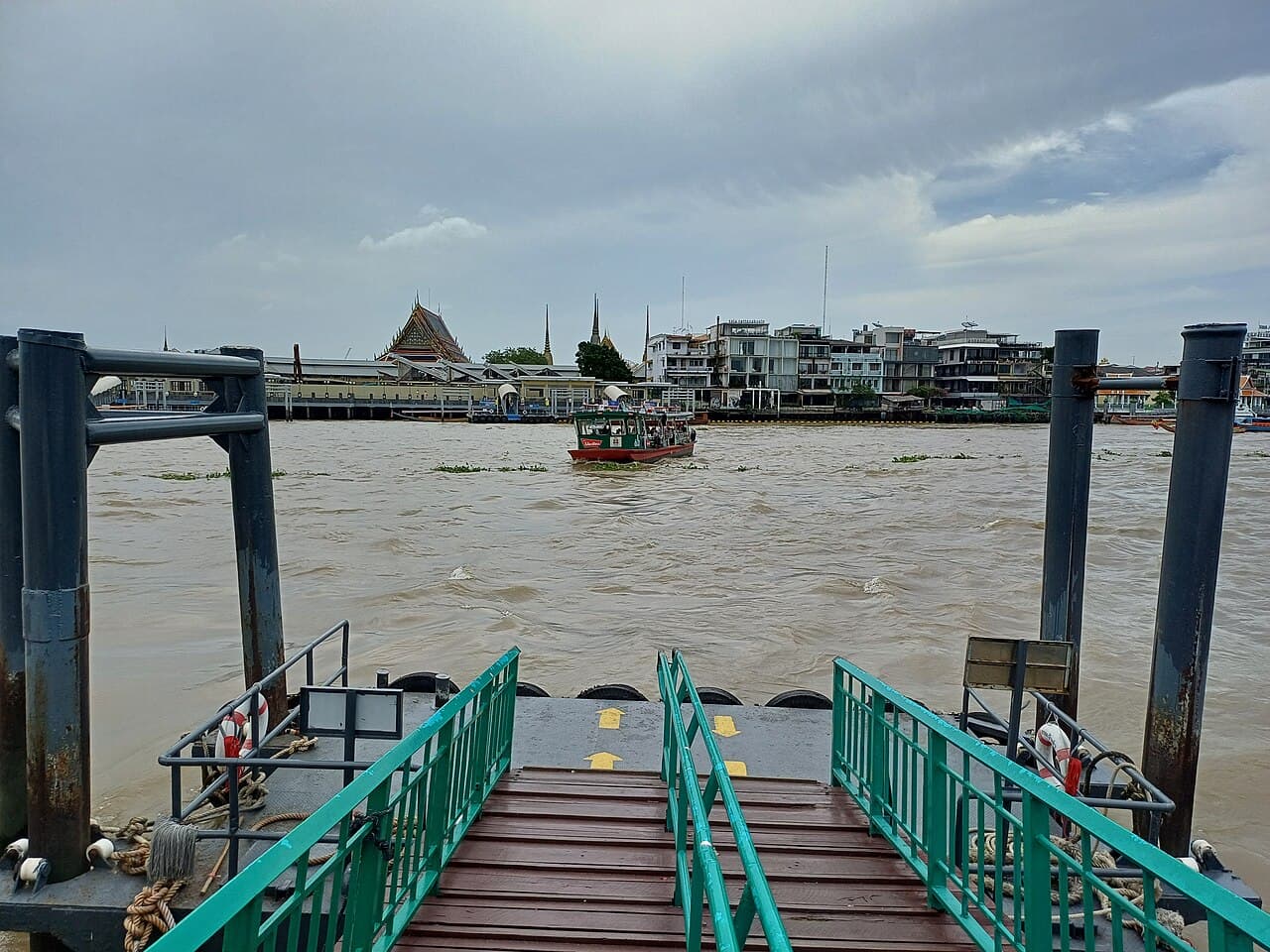 A long-tail boat on the Chao Phraya River with Bangkok temples behind