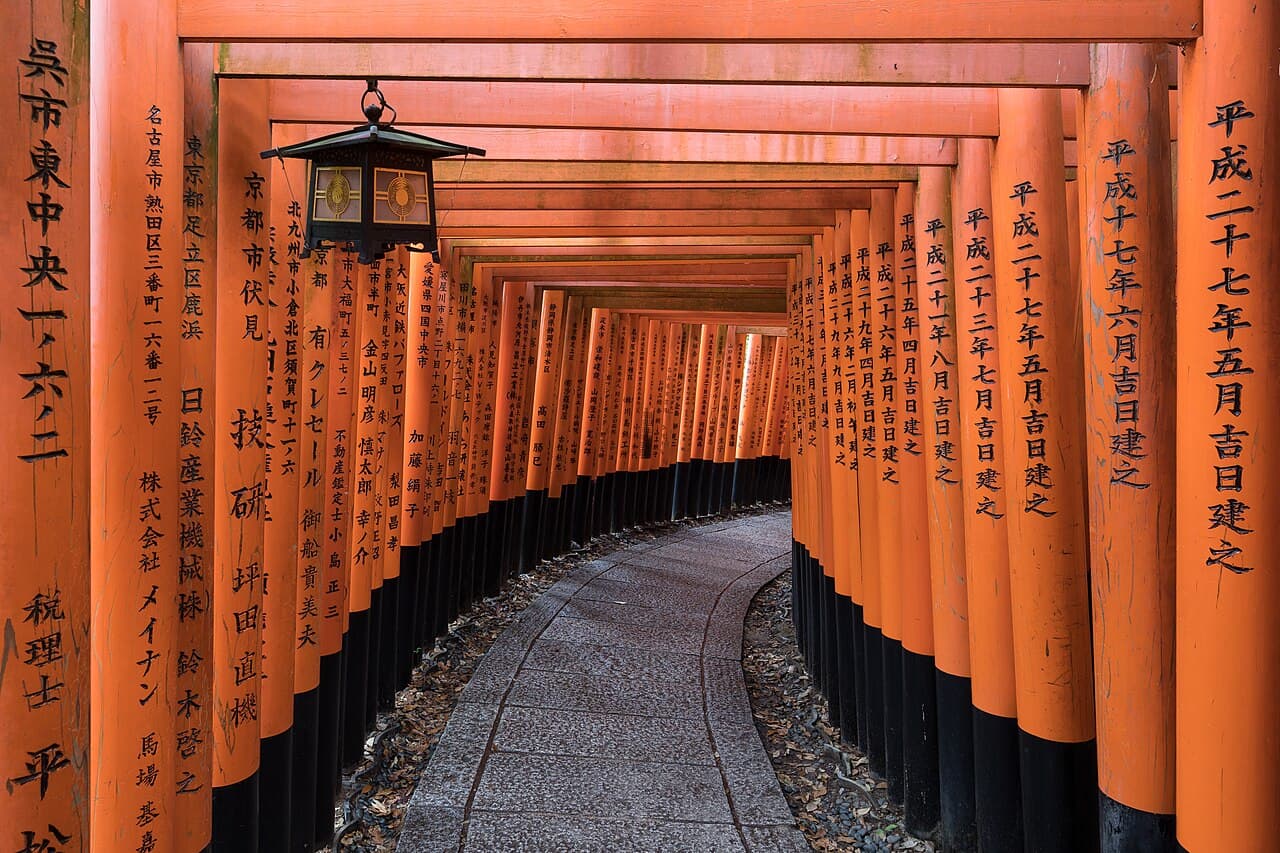 A tunnel of vermilion torii gates ascending the hillside at Fushimi Inari shrine, Kyoto