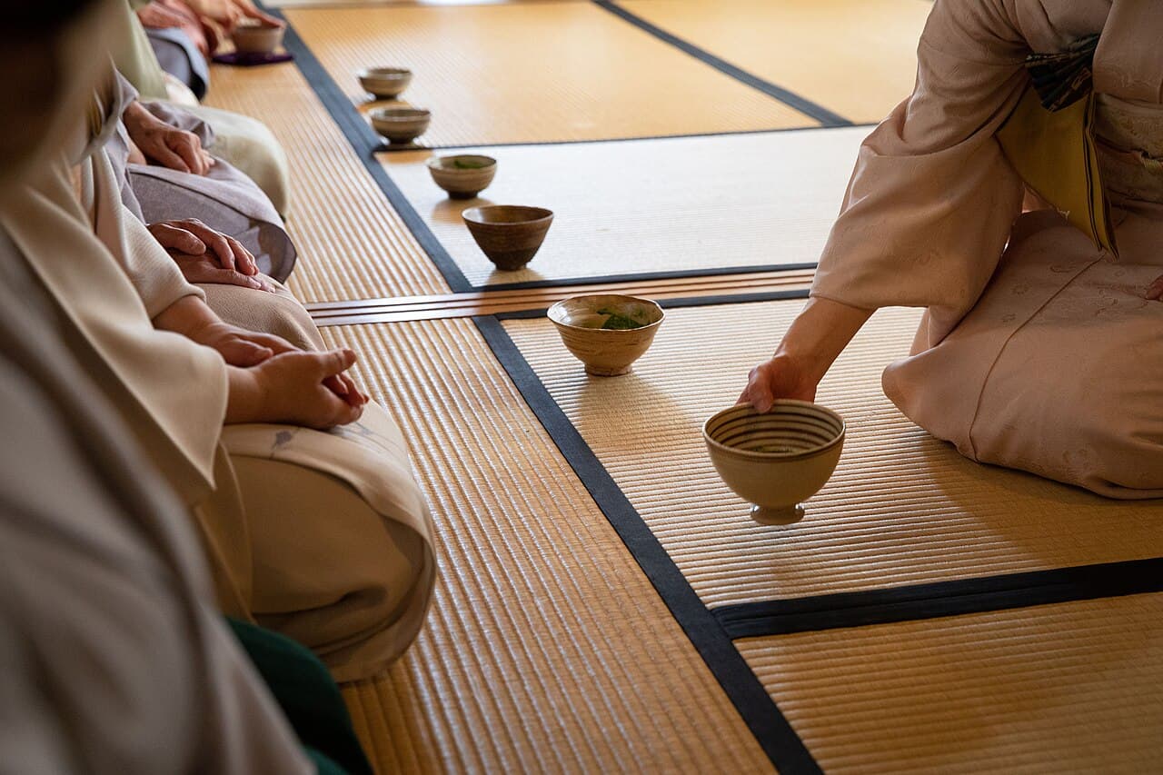 A bowl of frothy green matcha and a bamboo whisk set for a Japanese tea ceremony