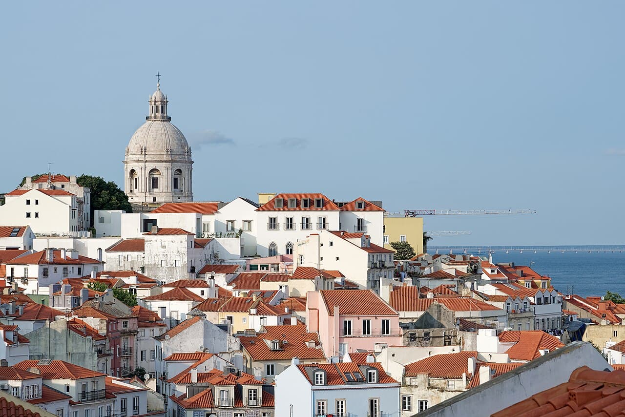 Terracotta rooftops of the Alfama district tumbling toward the Tagus River in Lisbon