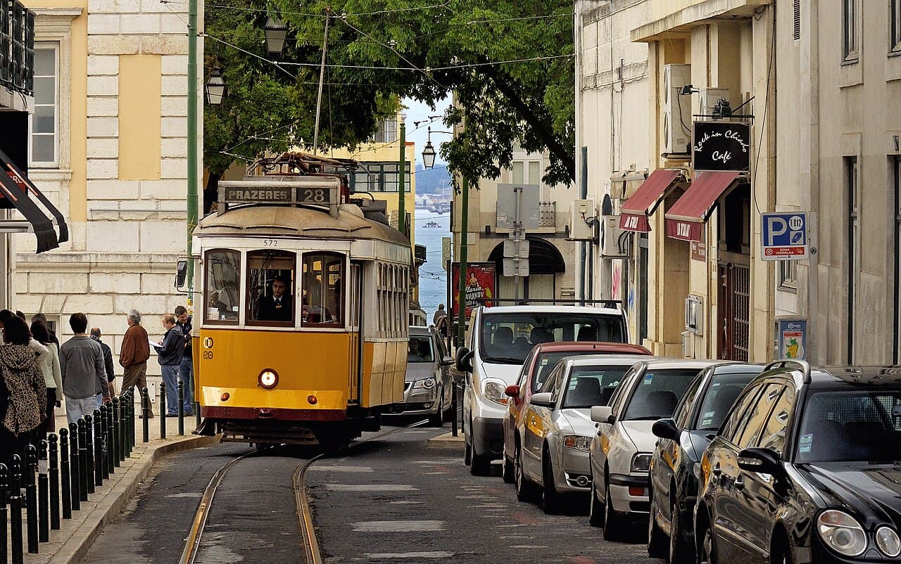A vintage yellow tram climbing a narrow tiled street in Lisbon