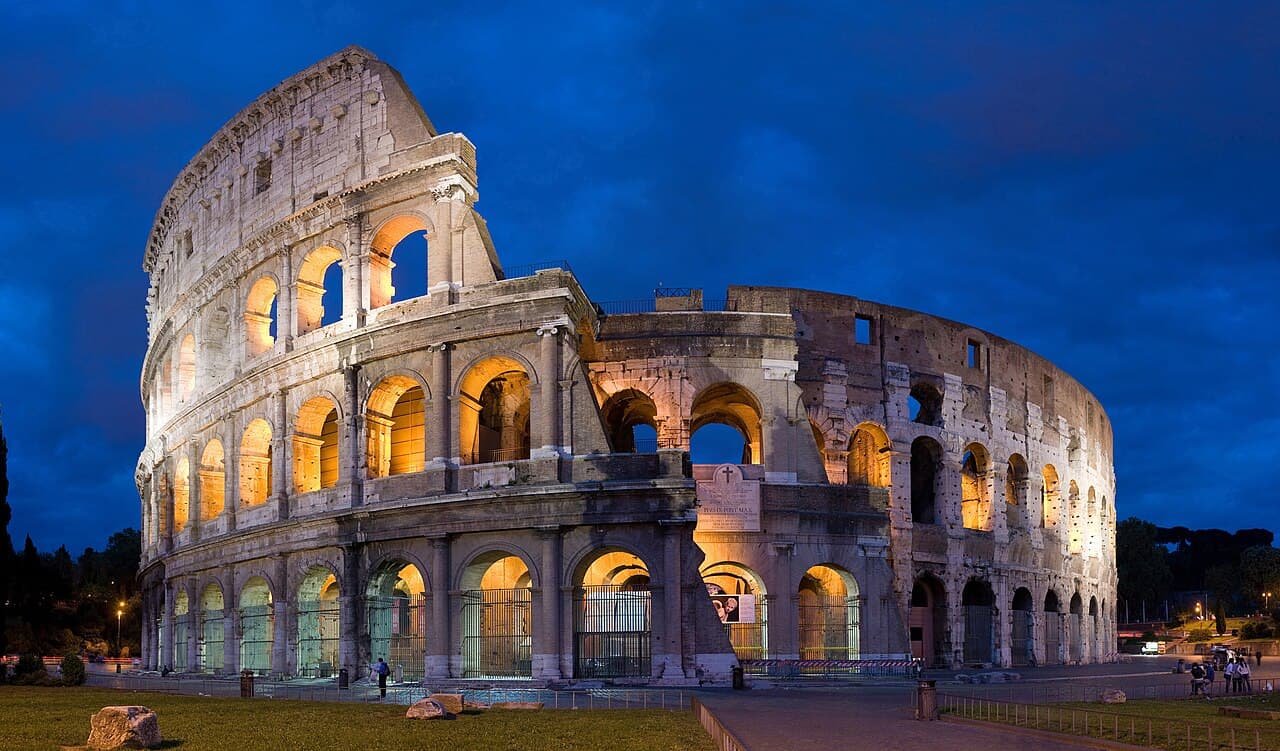 The ancient Colosseum amphitheatre lit against a dusk sky in Rome