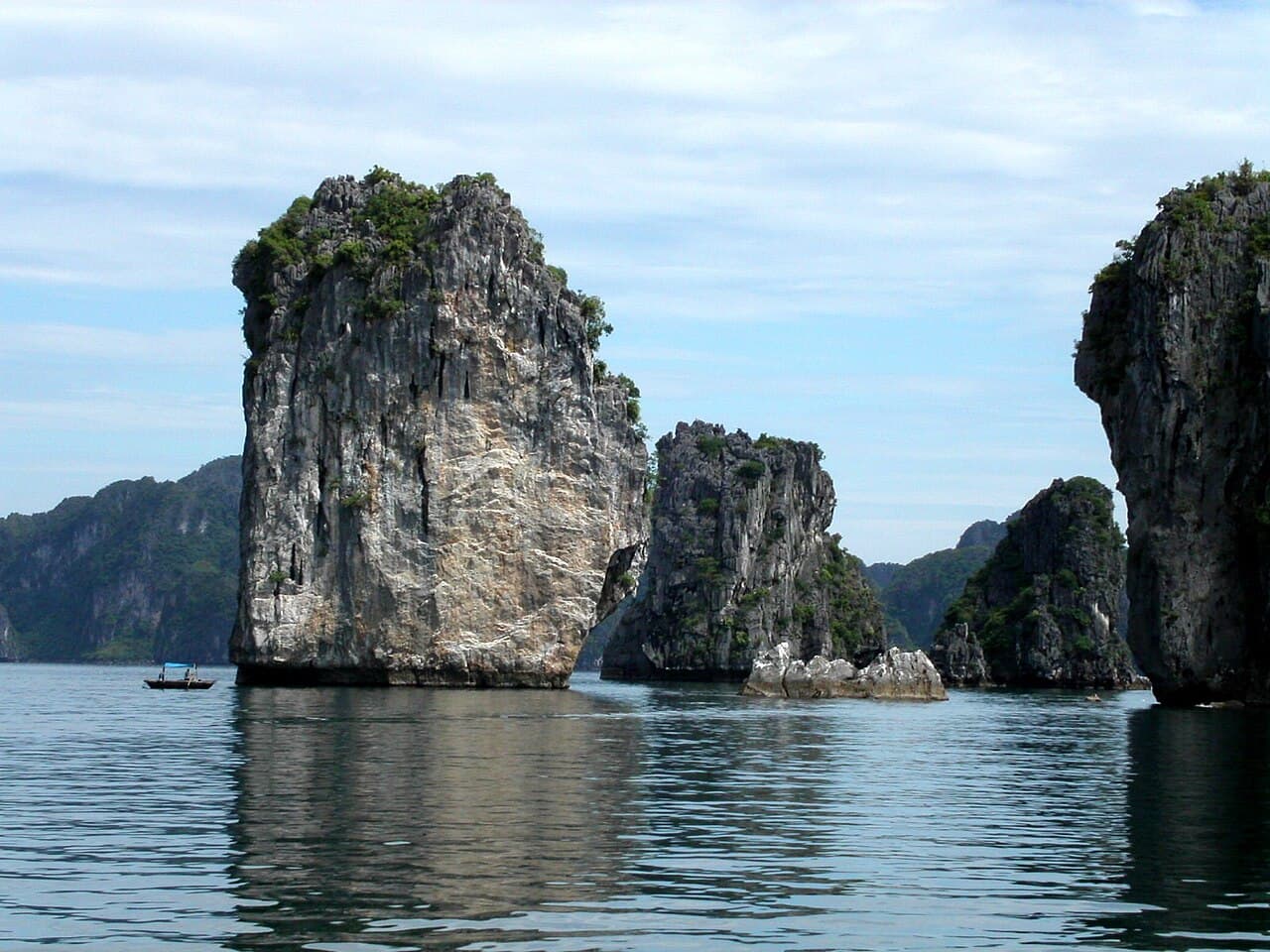 Limestone karst islands rising from the calm green water of Ha Long Bay, Vietnam